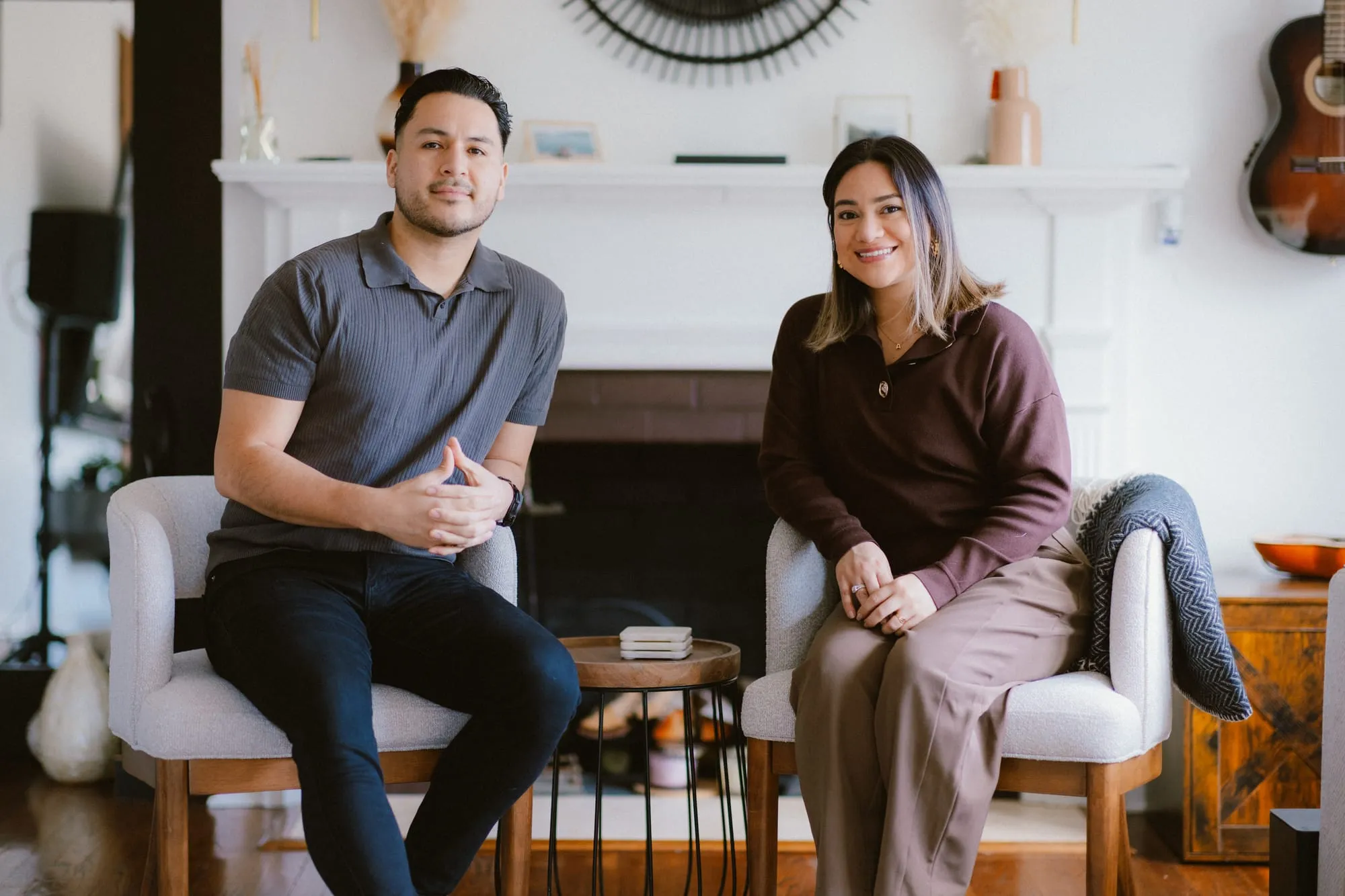 Andres Samaniego and Andrea Blanco sitting in two armchairs in front of a fireplace